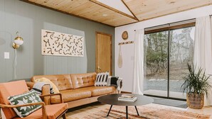 Ein gemütliches Wohnzimmer mit einer Ledersofa, einem Couchtisch und einem großen Fenster mit Vorhängen.
