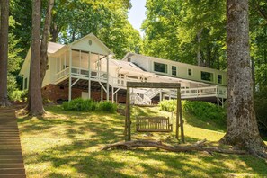 A house with a porch, a wooden swing, and a staircase leading to a deck.
