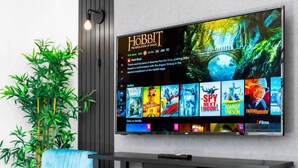 A flat-screen TV mounted on a wall displaying a movie selection interface with a prominent 'The Hobbit' title.