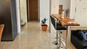 A modern kitchen with a built-in refrigerator, a wooden dining table with bar stools, and a potted plant. - Holiday Home Sunrise - Three Bedroom Holiday Home (Omis)
