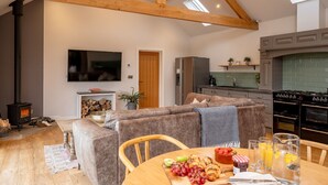A cozy living room with a fireplace, a sofa, a dining table with breakfast items, and a kitchen with modern appliances.