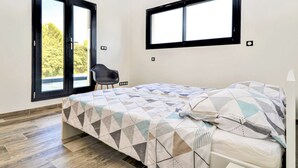 Ein Schlafzimmer mit einem Bett, einem Sessel und zwei Fenstern.