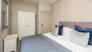 A bedroom with a bed, bedside tables, a wardrobe, and a hanging light fixture.