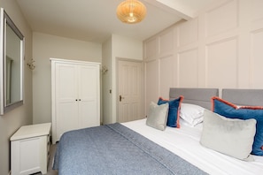 Un dormitorio con cama, mesitas de noche, armario y lámpara colgante.
