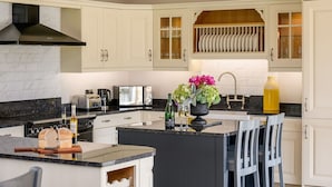 A kitchen with white cabinetry, a central island, a black countertop, and a backsplash.