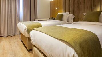 Habitación de hotel con dos camas, un armario de madera y una cortina.