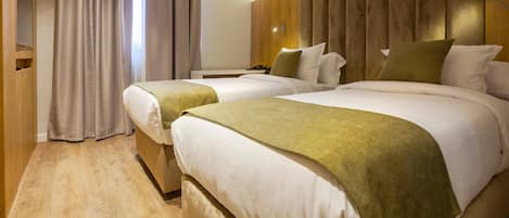 A hotel room with two beds, a wooden wardrobe, and a curtain.