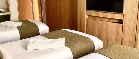 A hotel room with two beds, a television, and a wooden wardrobe.
