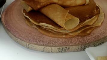 A stack of crepes on a round plate with a Nutella jar in the background.