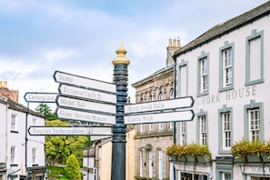 Un cartel de indicaciones con múltiples flechas que señalan diversas atracciones locales como 'Toilets', 'Richmond Castle', 'Georgian Market Hall', 'Green Howards Museum', 'River Swale Falls', 'Castle Walk' y 'York House'.