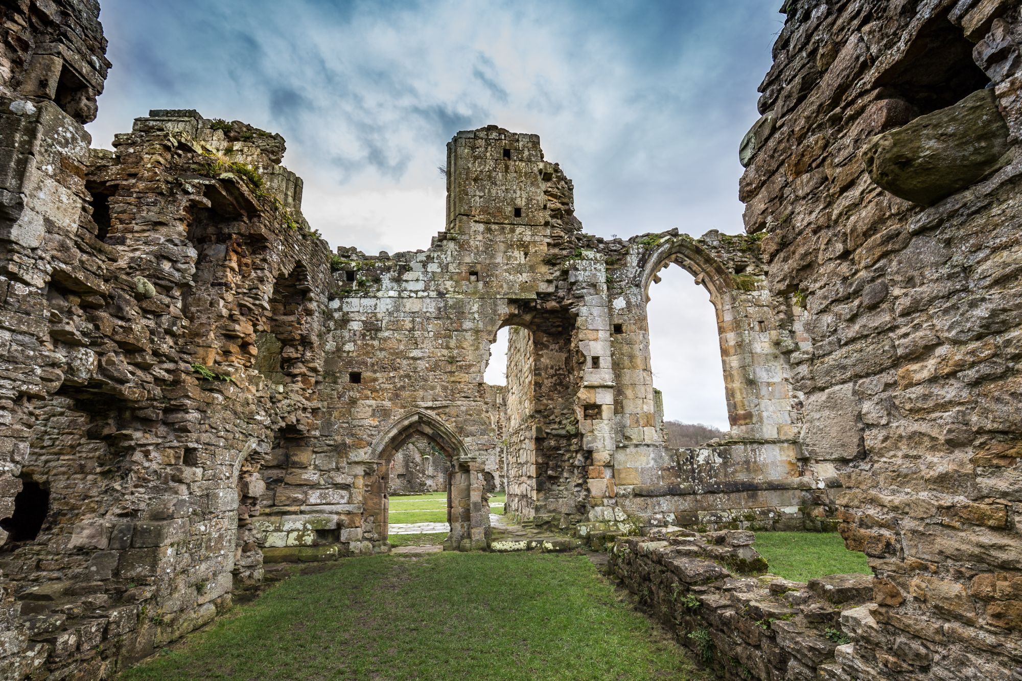 The interior of a historic stone building with arches and ruins.