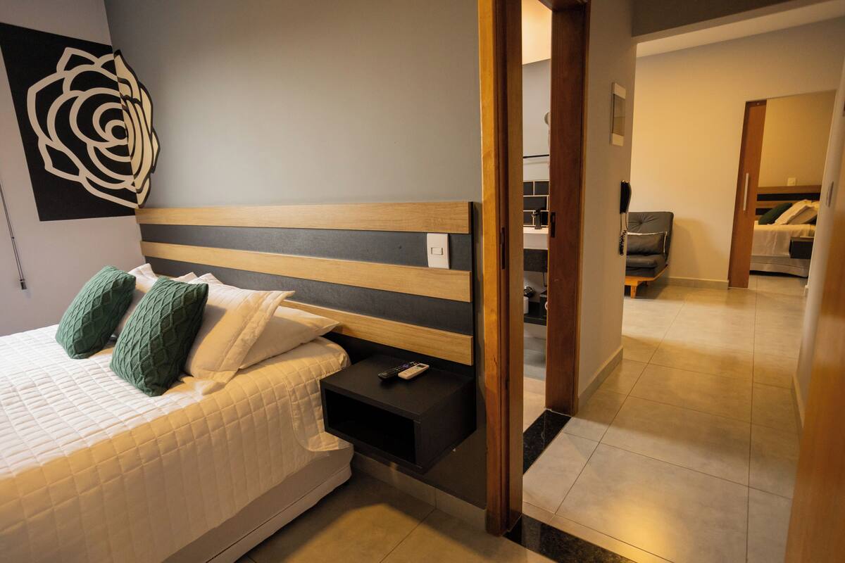 Un dormitorio moderno con cama, mesita de noche y una obra de arte colgada en la pared.
