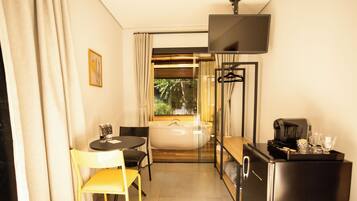 Quarto de hotel compacto com área de refeições, banheira, televisão de tela plana e refrigerador.