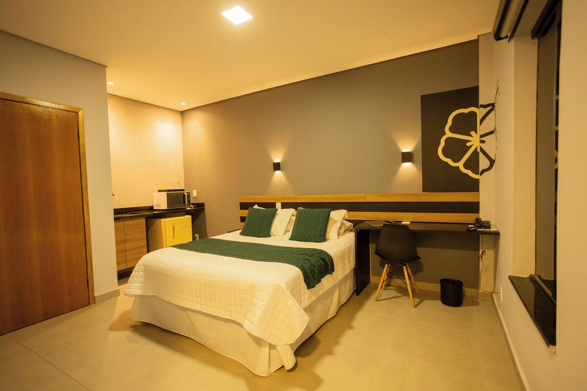 Un dormitorio con cama, escritorio, silla, armario e iluminación en la pared.