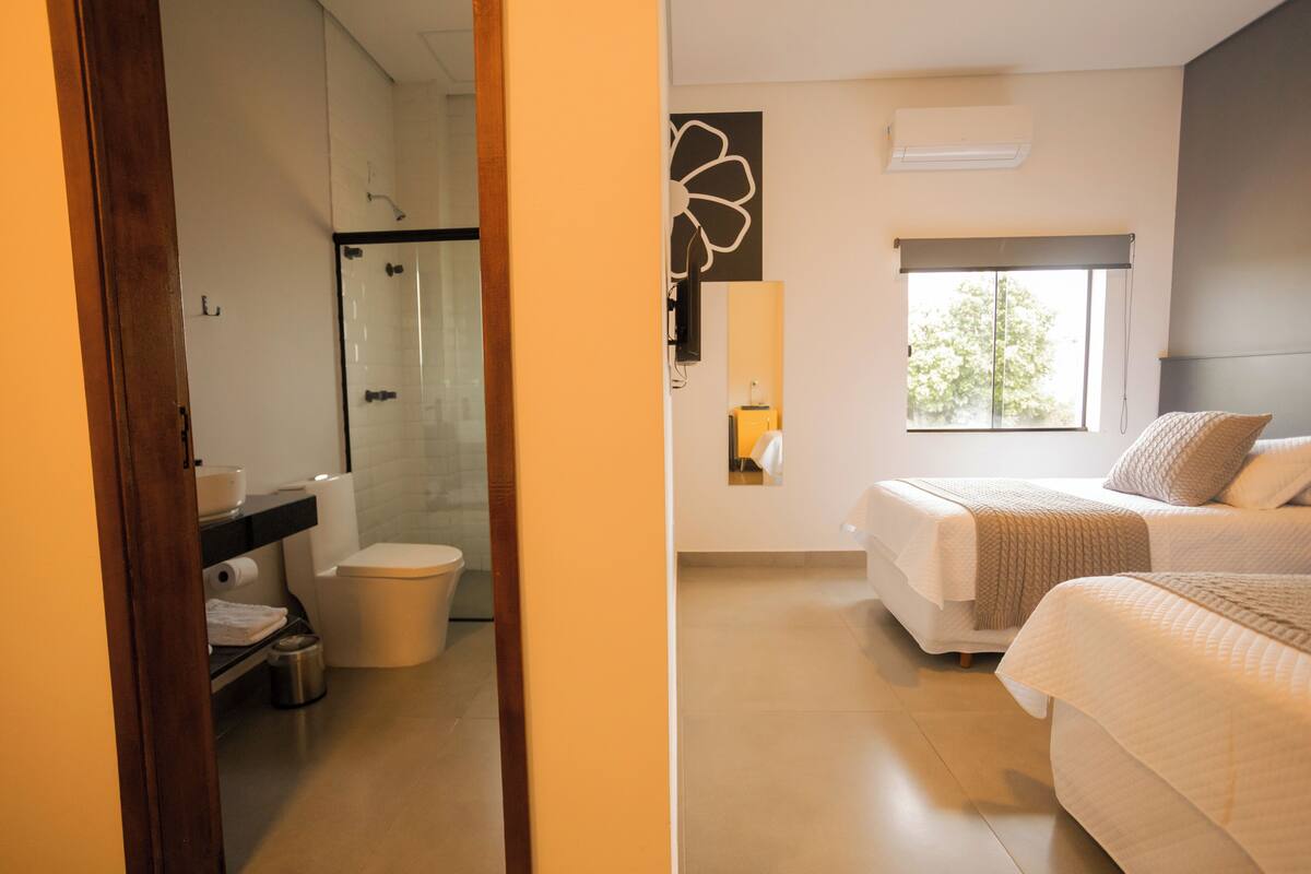 Habitación de hotel con ducha, inodoro y cama con vistas al exterior.