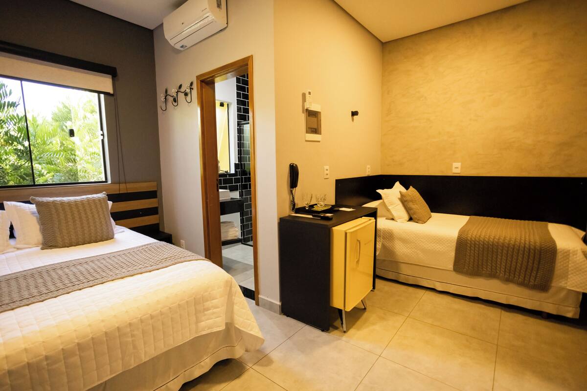 Una habitación de hotel con cama, mesita de noche, escritorio y armario.