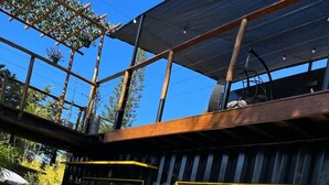 A modern building with a glass facade, a metal gate, and a flower bed with colorful flowers. - Hotel Flores de Holambra (Holambra)