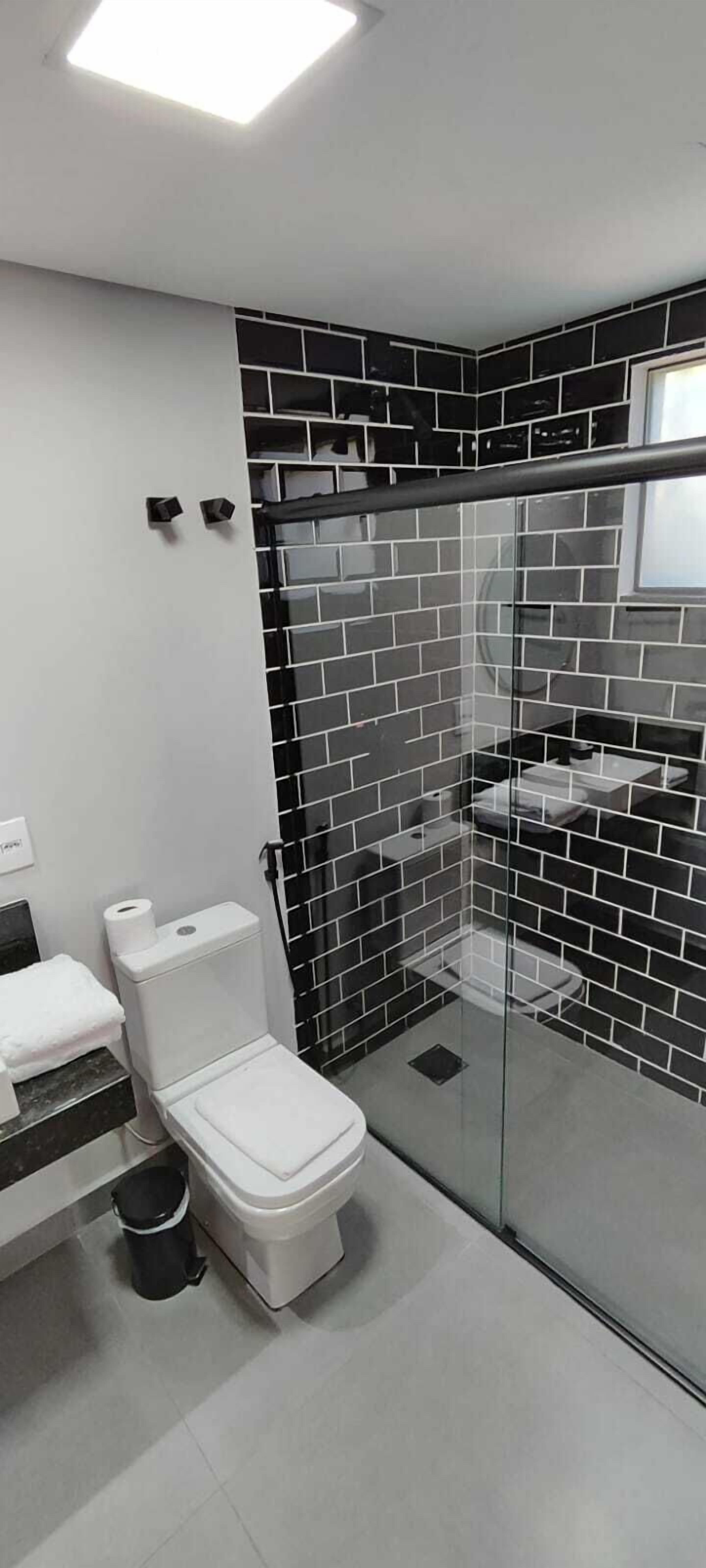 Un baño moderno con inodoro, lavamanos y cabina de ducha con mampara de vidrio.