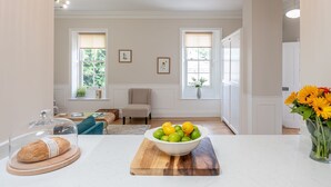 A spacious living room with a sofa, a dining table, and a kitchen area with a bowl of fruit on the counter. - The Swaledale -  a cottage that sleeps 2 guests  in 1 bedroom (Richmond)