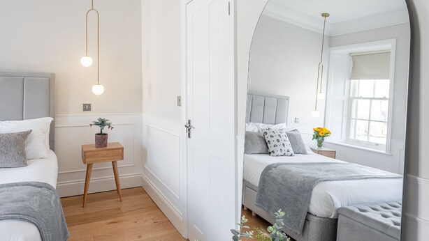 A bedroom with two beds, a bedside table with a plant, and a window with a view. - The Swaledale -  a cottage that sleeps 2 guests  in 1 bedroom (Richmond)