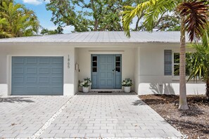 A single-story house with a light blue garage door, a matching front door, and a small porch area with two potted plants.