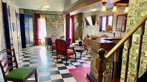 A hotel lobby with checkered flooring, wooden chairs, a staircase, and wallpaper with dollar bill designs. - Actual Pretty Boy Floyd Hideout  Lake Erie, MI (Luna Pier)