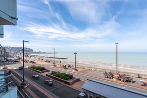 Eine Uferpromenade mit Blick auf das Meer, ausgestattet mit einem gepflasterten Weg, Bänken und Straßenlaternen.