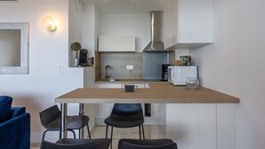 Une cuisine moderne avec des armoires blanches, une hotte de cuisinière en acier inoxydable et un petit îlot central doté de tabourets de bar.