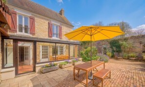 Ein Haus mit Terrasse, Holzmöbeln und einem großen gelben Sonnenschirm.