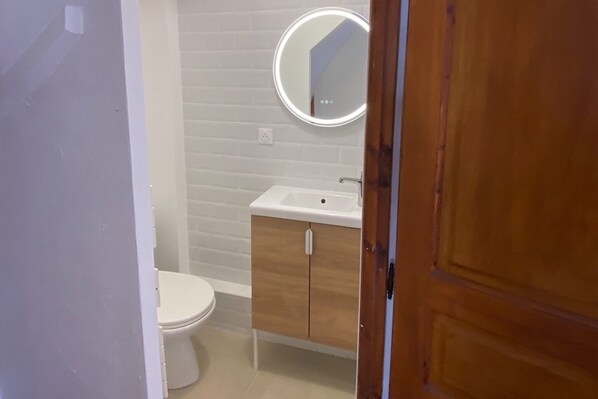 Ein kleines Badezimmer mit Toilette, Waschbecken und Spiegel.