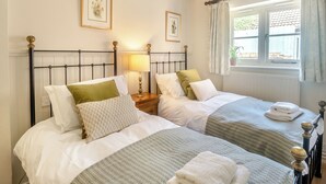 A double room with two beds, a window with curtains, and a lamp on the nightstand. - 2 bedroom accommodation in Overstrand, near Cromer (Overstrand, near Cromer)