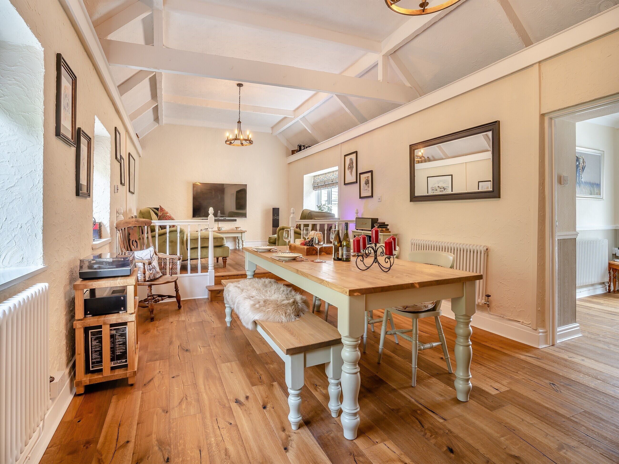 Un salón espacioso con piso de madera, una mesa de comedor y una escalera que sube a un nivel superior.