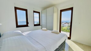 Ein Schlafzimmer mit zwei Betten, einem großen Kleiderschrank und einem Balkon mit Blick.