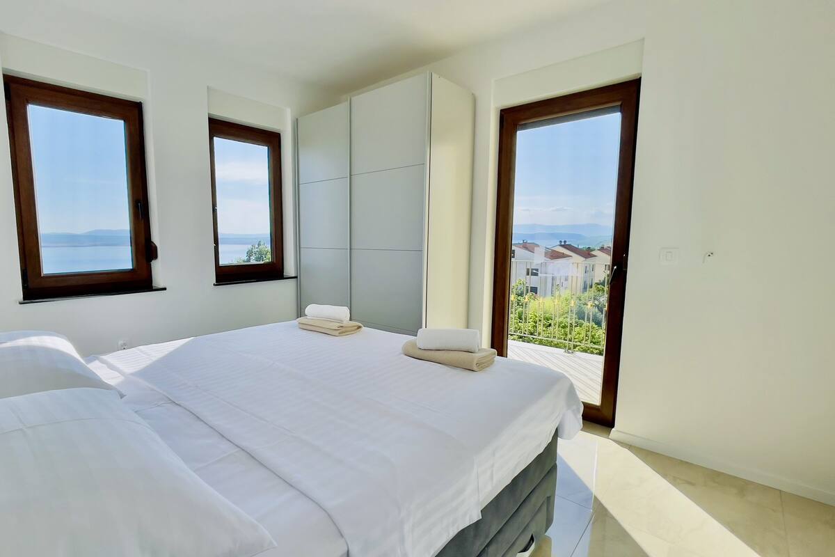 A bedroom with two beds, a large wardrobe, and a balcony with a view.
