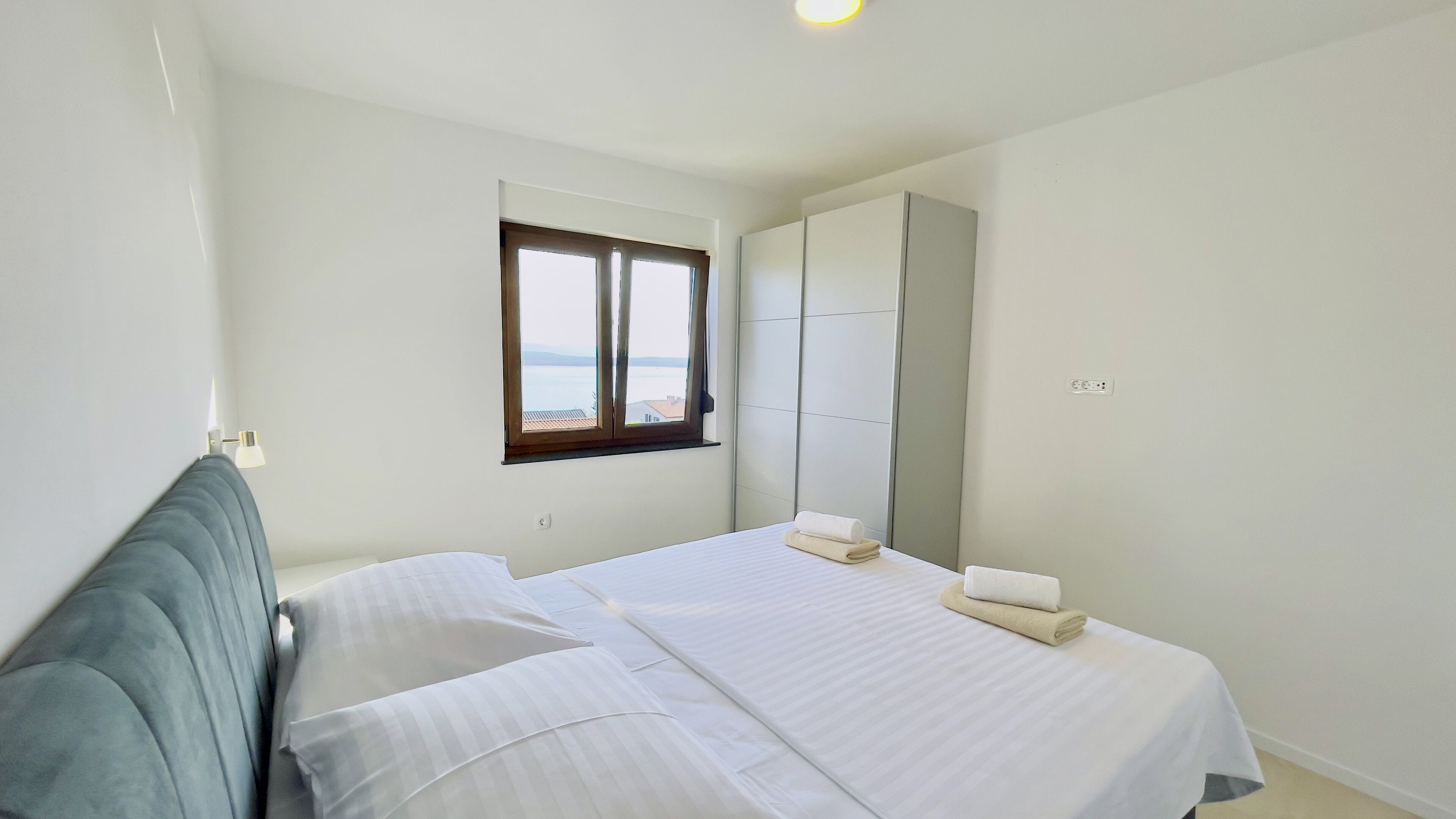 Une chambre à coucher avec un lit, une fenêtre donnant sur un beau paysage et une armoire.