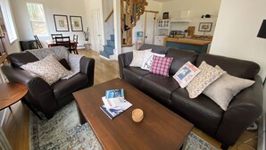 Ein Wohnzimmer mit zwei Ledersofas, einem Couchtisch und einer Treppe, die in eine Küche führt.