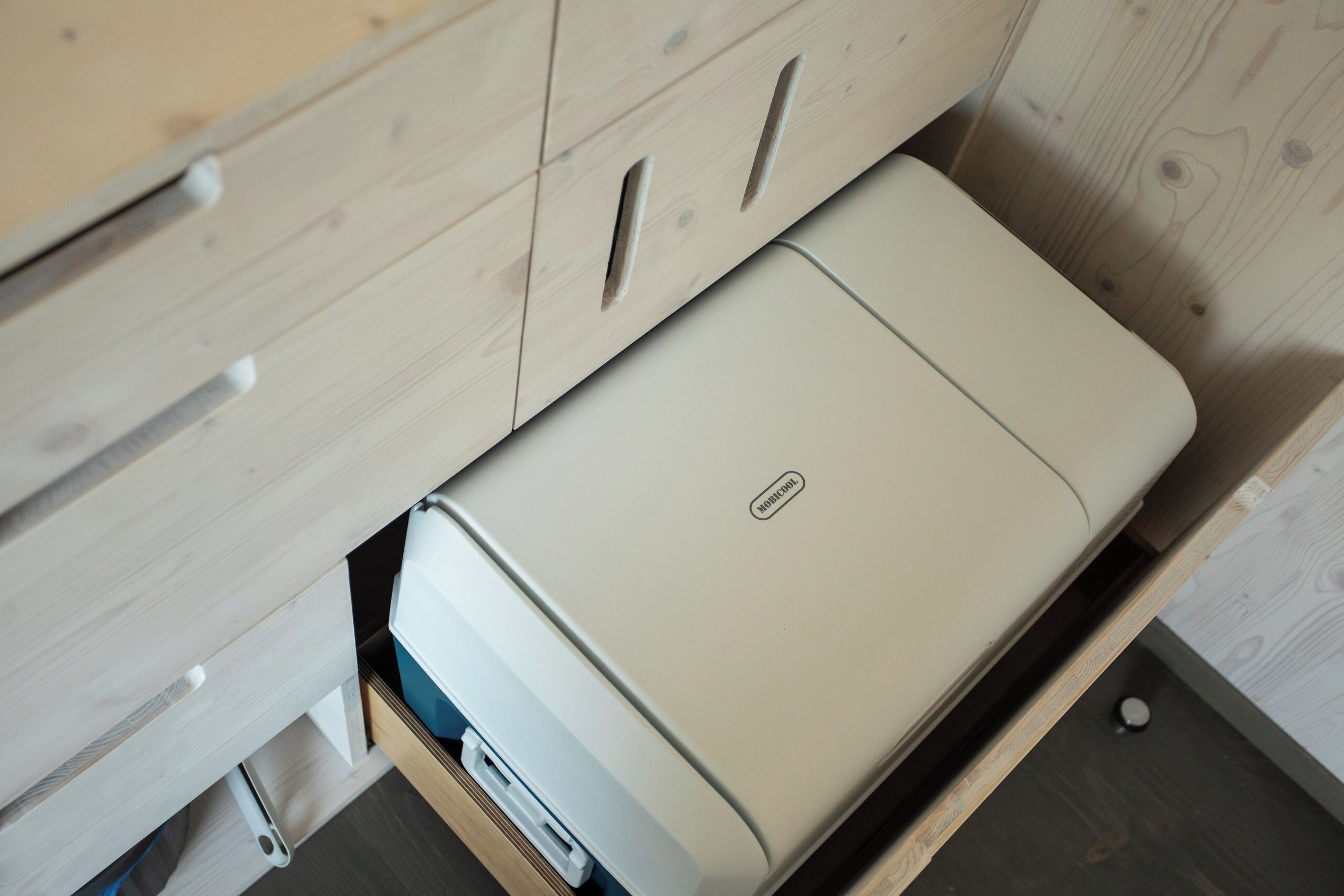 A compact, modern printer placed in a wooden drawer unit.