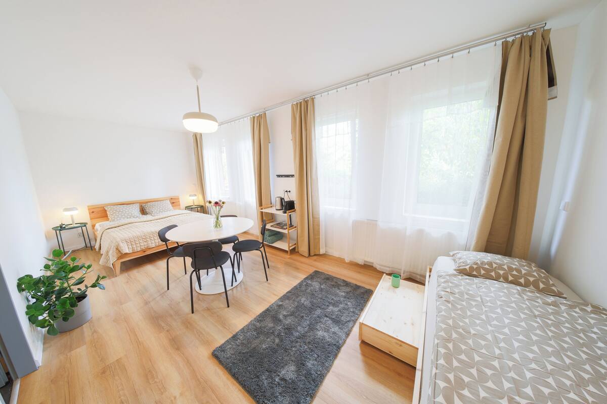 A modern bedroom with a bed, bedside table, lamp, and a small desk with a chair.