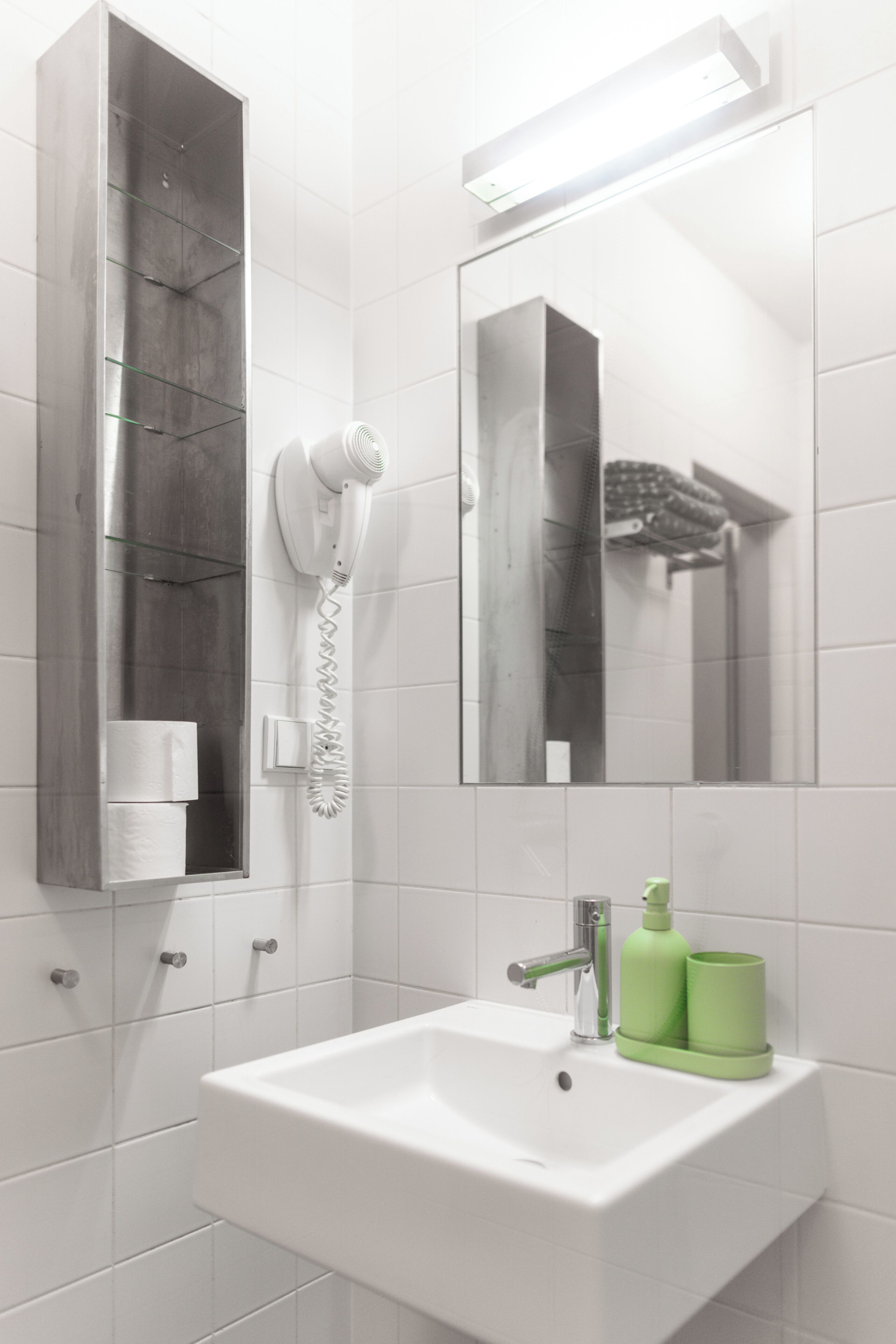 A bathroom with a white sink, a mirror, a hairdryer, and a towel rack.
