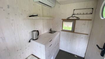 A compact kitchen with a built-in stove, a small window, and a hanging rack.