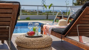 Ein Poolbereich mit Liegestühlen, einem Korbtisch und einem Tablett für Getränke sowie Blick auf den Pool.