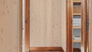 A room with wooden walls and floors, a built-in shelf unit, and a door leading to another room. - Secluded Cottage on 85 Acres – Peaceful Country Retreat Surrounded by Nature (Walton)