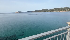 Une vue sur la côte, avec une eau turquoise et limpide, une île lointaine et un paysage vallonné.