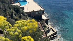 Un hôtel situé sur la côte, doté d’une piscine, de plusieurs balcons et offrant une vue sur la mer.