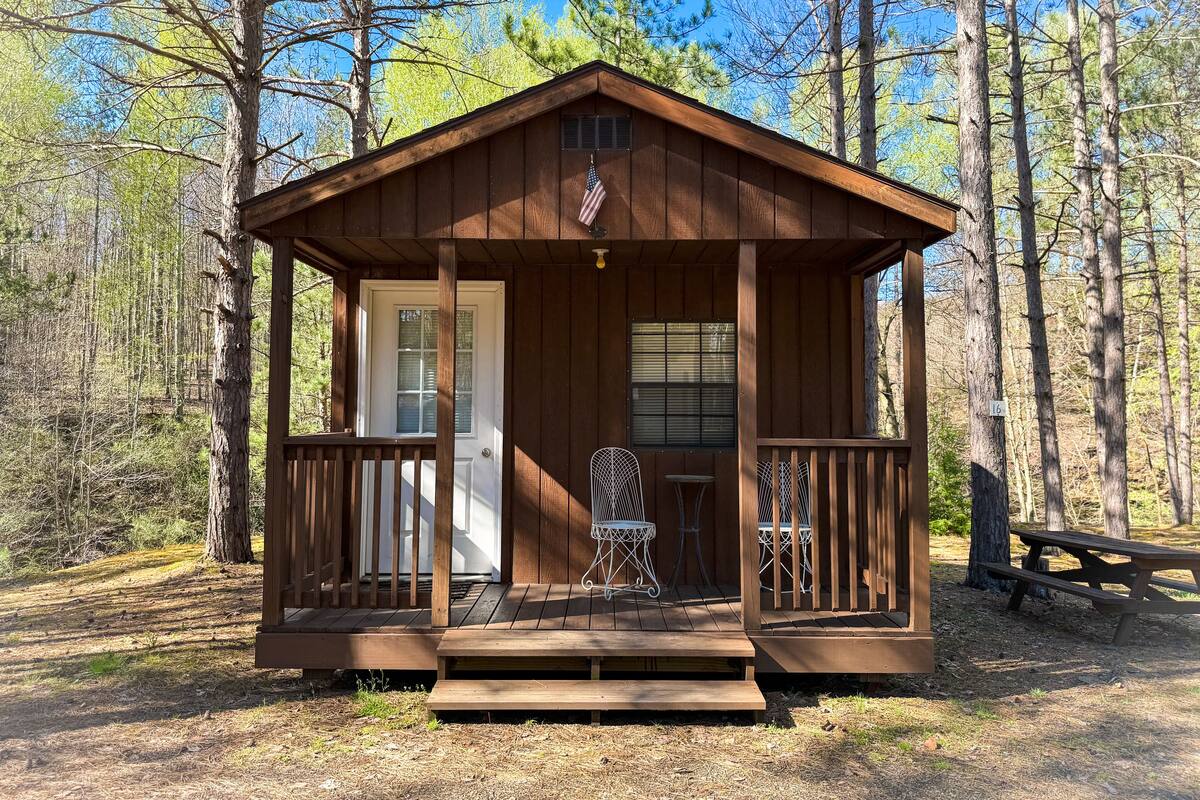 Een houten chalet met een veranda, een deur en een raam.