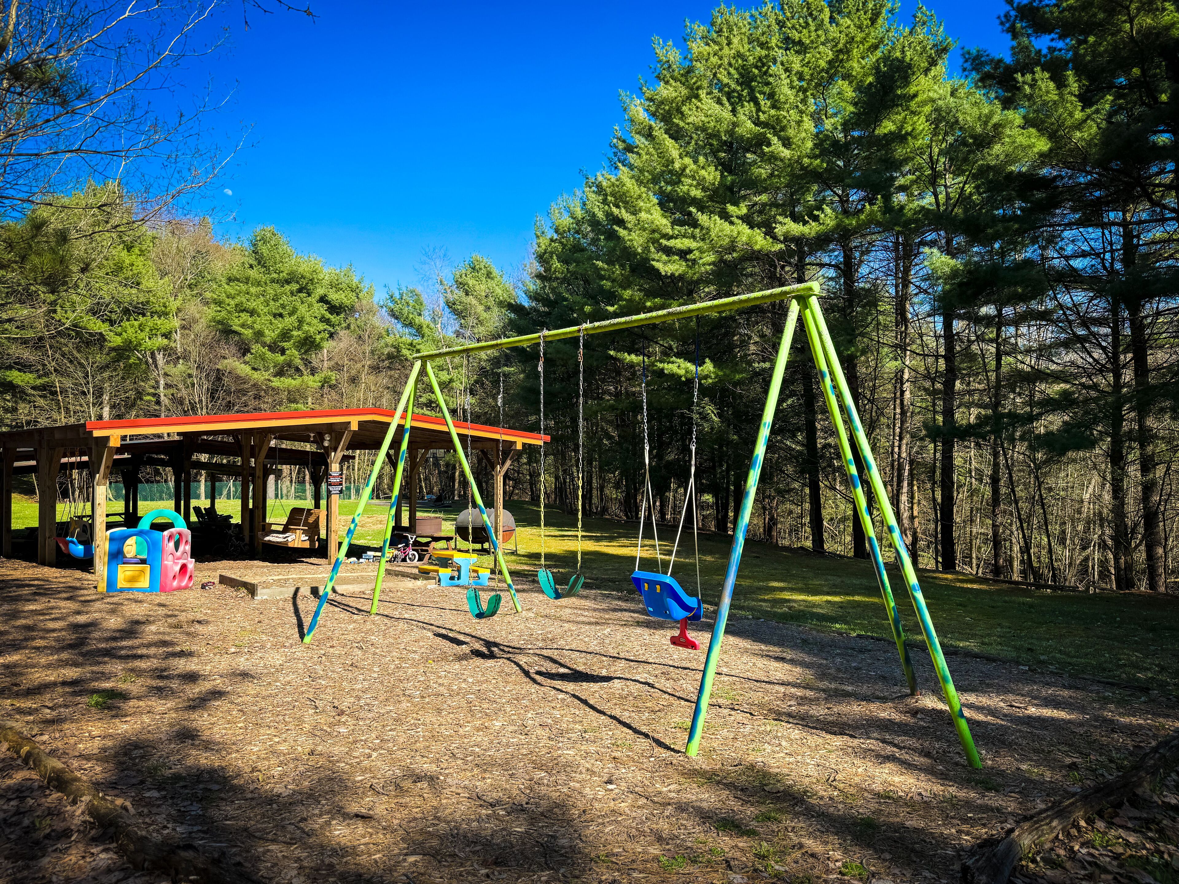 A playground with swings and a covered seating area.