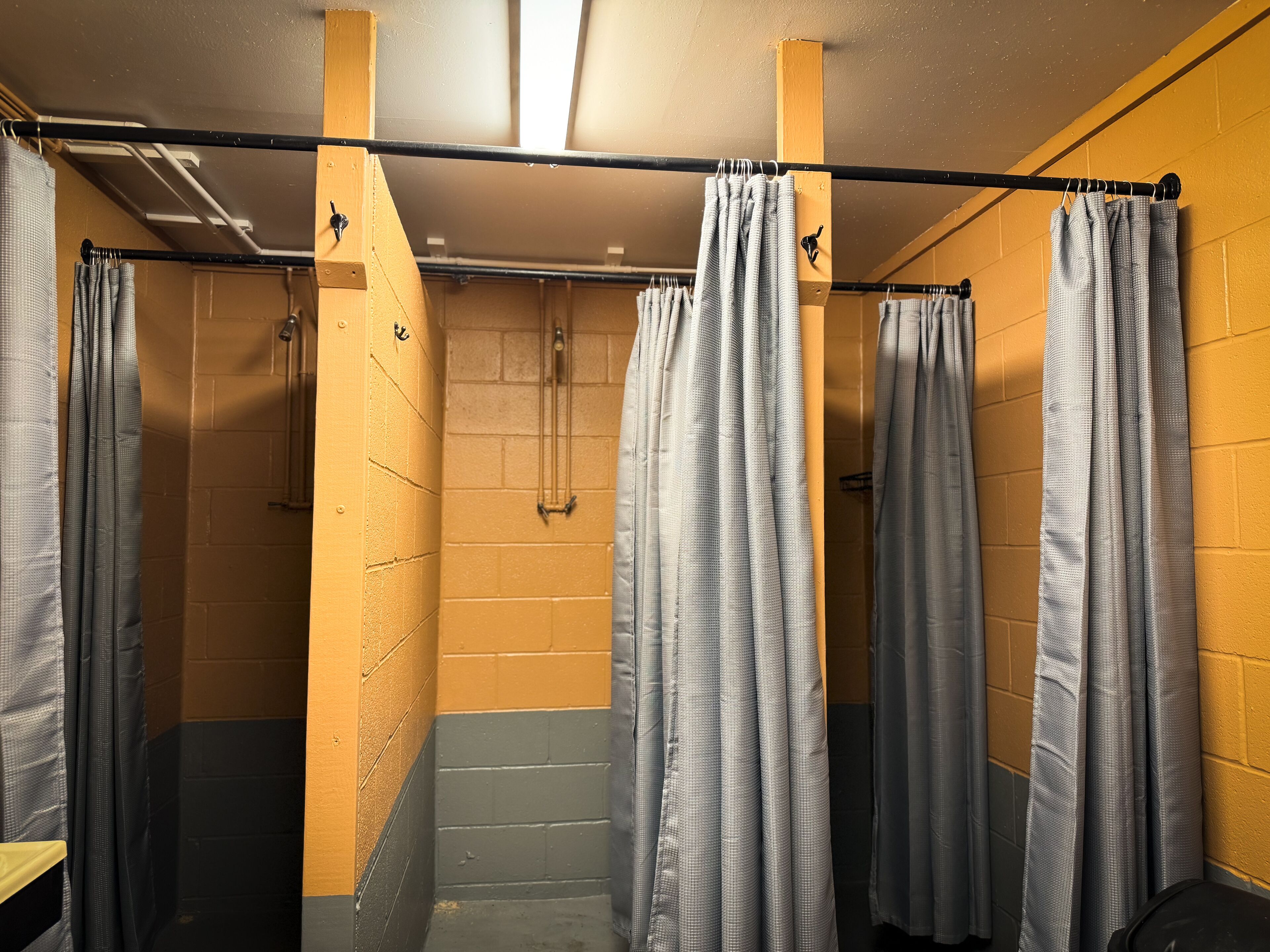 A public restroom with multiple stalls, each with a shower curtain.