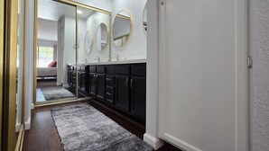 A bathroom with a large mirror, dark cabinets, and a gray rug. - Tempe 2Bdrm 2Ba by Papago Park A101 (Tempe)