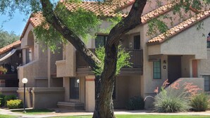 A multi-story building with a large tree in front, balconies, and a well-maintained lawn. - Tempe 2Bdrm 2Ba by Papago Park A101 (Tempe)