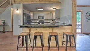Una cocina moderna con una isla central, taburetes de madera y vistas al exterior.